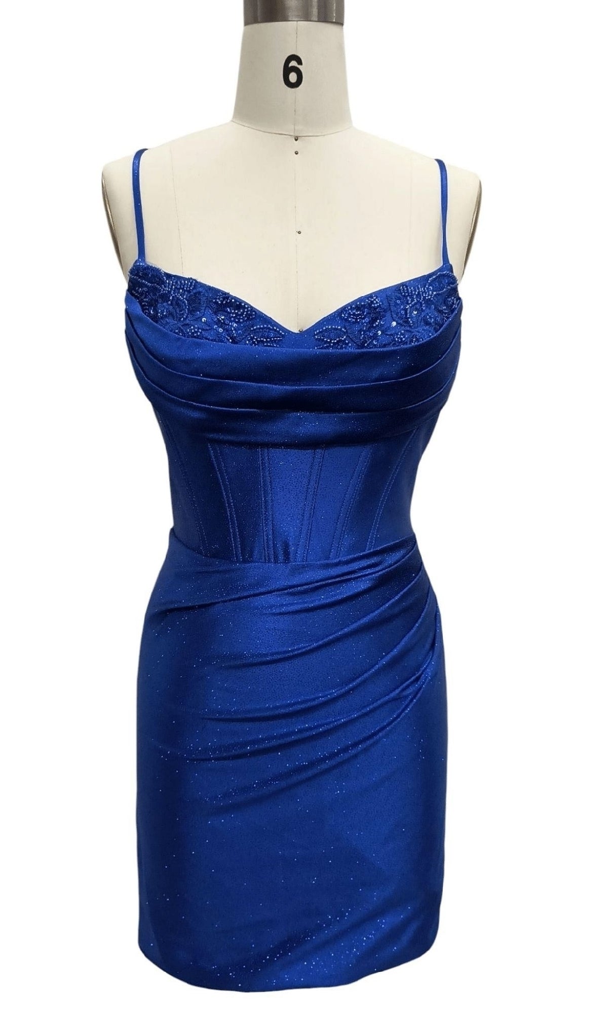 The Cowl-Neck Blue Hoco Dress: 12618 is a royal blue satin mini dress on a mannequin, showcasing thin straps, a corset-style bodice with lace accents, and draped detailing on the skirt.
